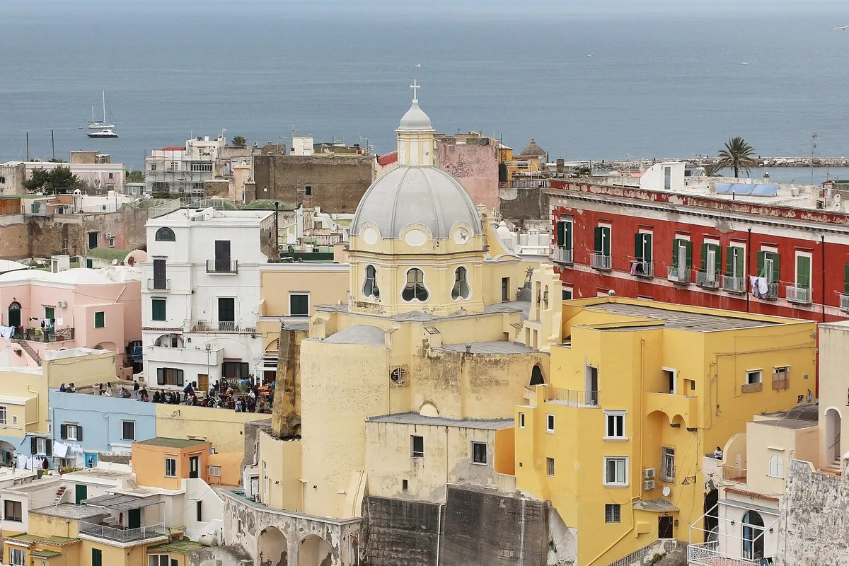 The pastel houses of Procida seen from above, with the dome of the Madonna delle Grazie