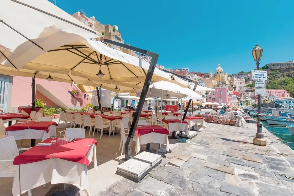 The Fuego terrace on the Corricella quay, with the parasols and the coloured houses behind
