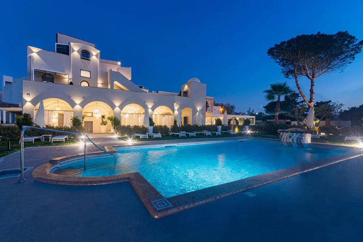 The lit pool and the facade of the Insula Boutique Hotel at dusk