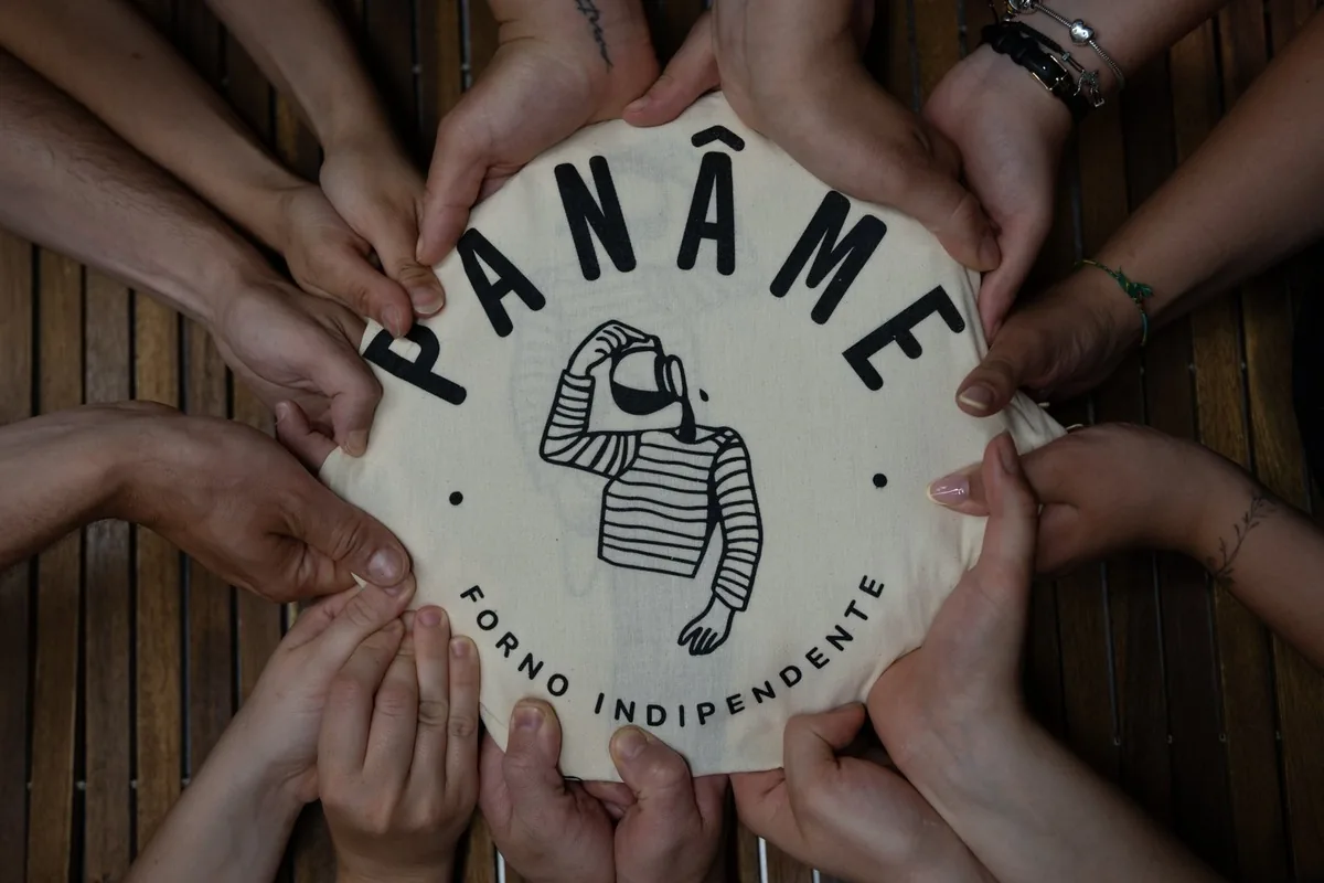 The plate with the Panam&eacute; Forno Indipendente mark, held by several hands around the table
