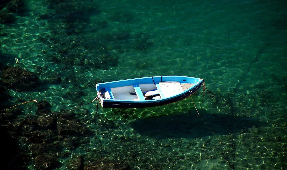 A gozzo moored on the clear water at Corricella, Procida
